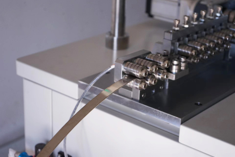 Stainless steel belt running through precision guide rollers on a forming line